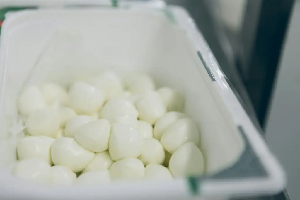 Small balls of fresh mozzarella piled in a white tub