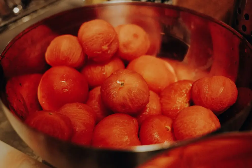 Whole peeled tomatoes piled in a stainless steel mixing bowl